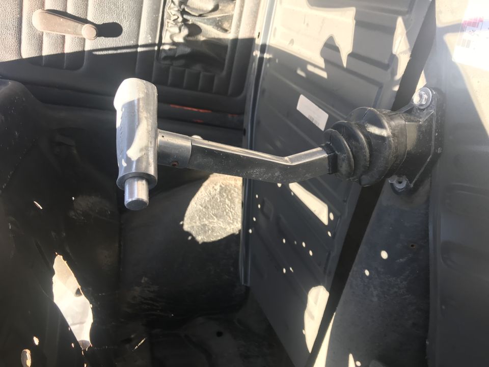 Close-up of a gear shifter mechanism with a silver knob and black rubber boot