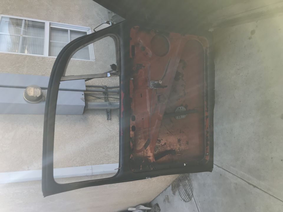 Interior of a vintage car door, rusty red metal, black trim.