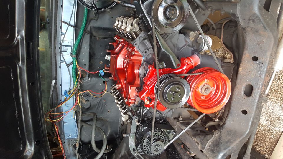 Overhead view of a red and black engine with belts, pulleys, and wiring.