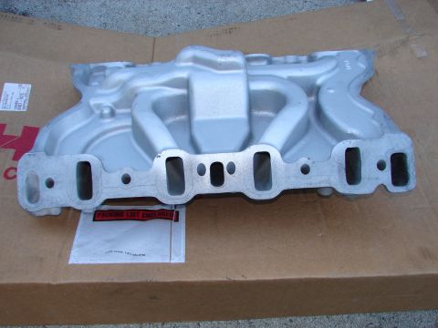 1973 Ford Ranchero - A silver aluminum intake manifold is shown from a front-side angle, resting on a brown cardboard box. A white packing list envelope is atta…