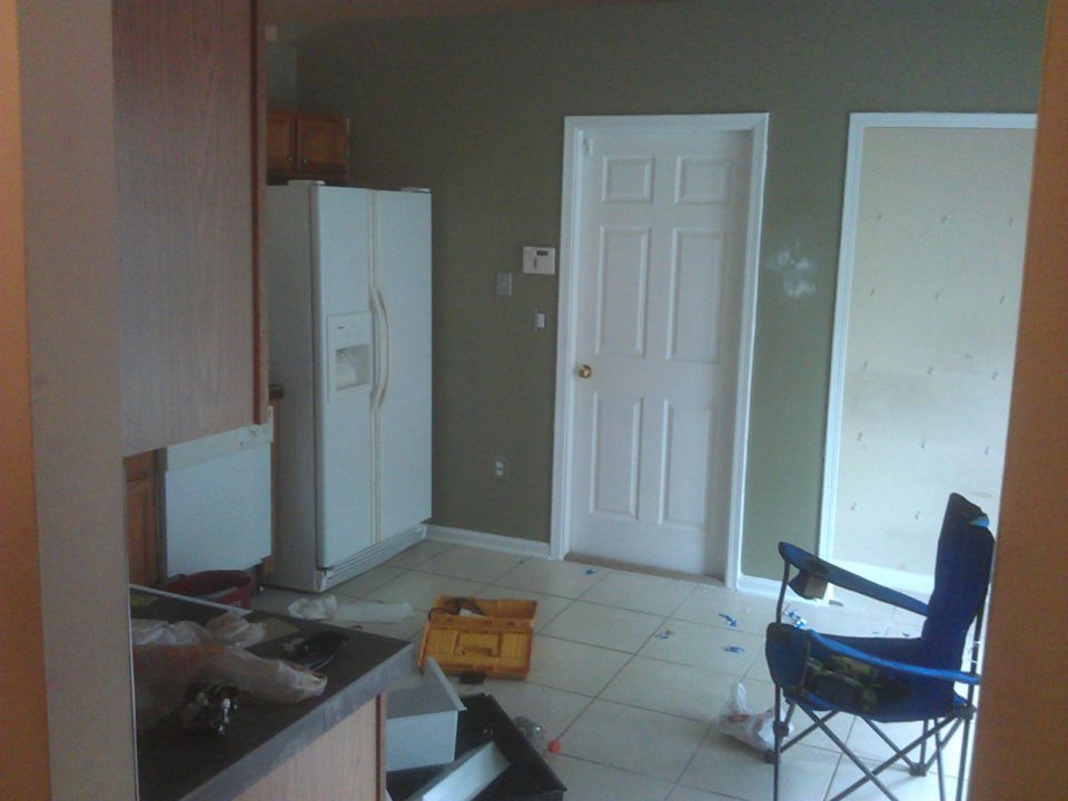 Unfinished kitchen with appliances, furniture, and tools