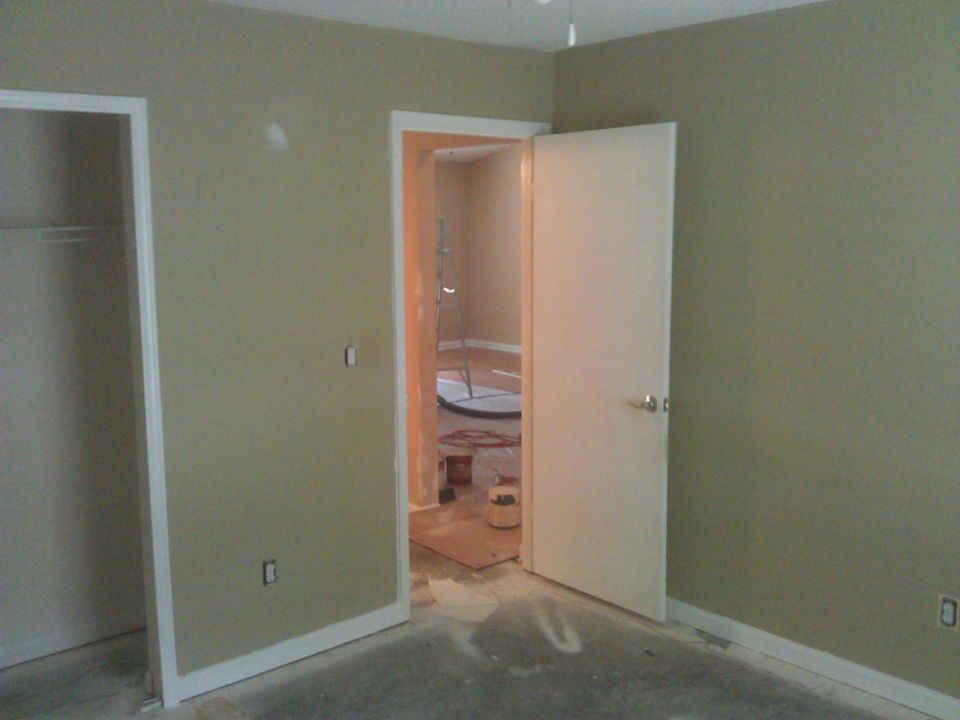 Interior scene of a room under renovation with beige walls and a white door.