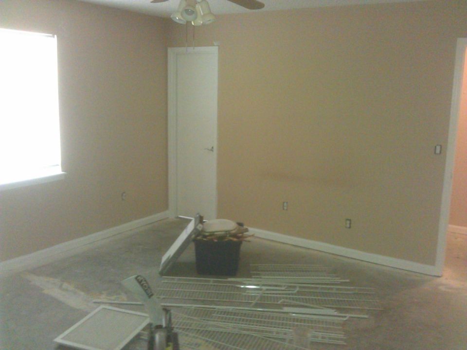 Empty room with window, door, and disassembled shelving units.