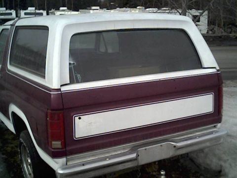 1983 Ford Bronco - The rear quarter panel of a two-tone Ford Bronco is visible, showing its distinctive body style.