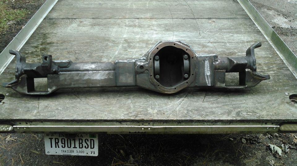 Modified metallic gray rear axle housing on a wooden trailer.