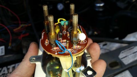 1985 Ford Bronco - A person holds a disassembled automotive gauge cluster with a circuit board and various electronic components visible. The circuit board ha…