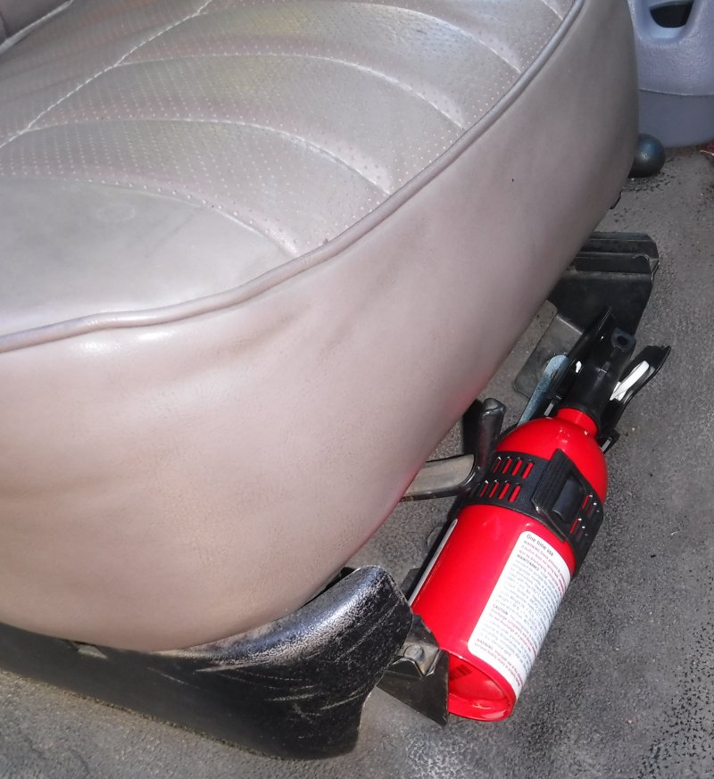 First Alert AUTO5 fire extinguisher, mounted to passenger seat front bolts; just enough clearance for seat slider & lever.