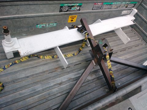1996 Ford Bronco - A white trailer tongue with a yellow and green camouflage strap attached to a black metal jack is loaded onto a gray metal truck bed.