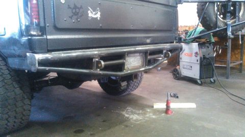 1992 Ford Bronco - The rear of a dark colored Ford Bronco with a custom steel bumper is shown in a workshop setting. A welding machine is visible to the right…