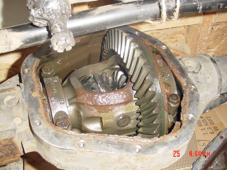 Open differential housing showing ring-and-pinion gear and carrier, heavy surface rust inside