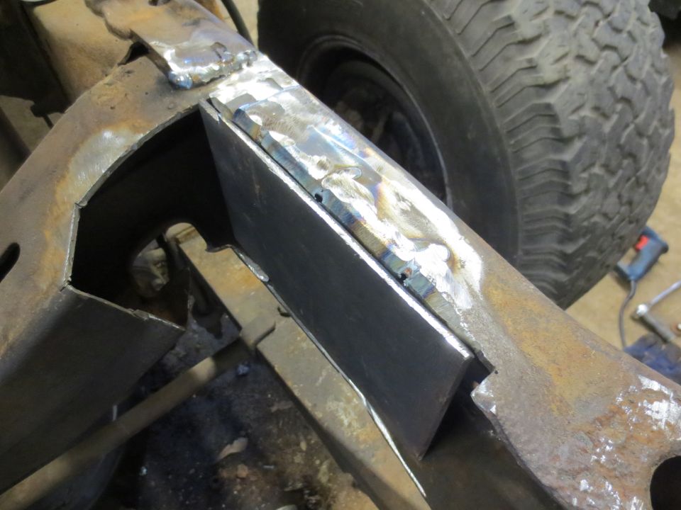 Welded metal plates reinforcing a vehicle frame next to a tire.