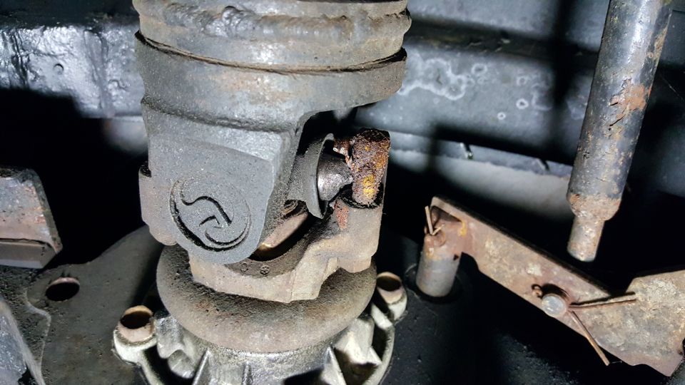 Close-up of a rusty universal joint on a vehicle driveshaft.