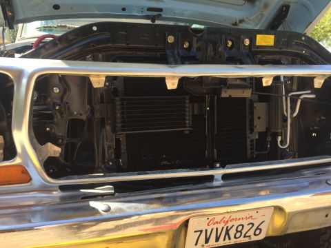 1978 Ford Bronco - The front grille and engine bay of a classic Ford truck are visible, with the hood open. The radiator and air conditioning components are e…