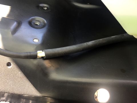 1978 Ford Bronco - A black rubber hose with a white plastic connector is shown running across a black metal surface. There are several threaded mounting point…