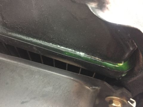 1978 Ford Bronco - A close-up view shows green coolant pooled along the top edge of a radiator or similar component, with a black textured surface above it.