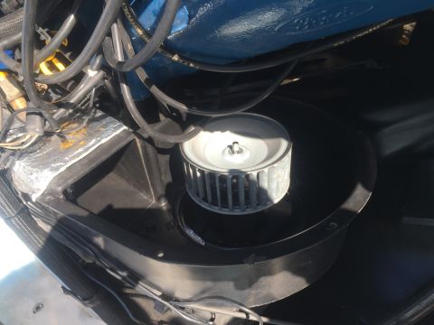 1978 Ford Bronco - A close-up view of the blower motor assembly and surrounding engine components in a vehicle. The blower motor housing is black, with a silv…