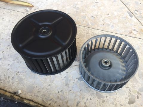1978 Ford Bronco - A black blower wheel housing sits next to a silver blower wheel on a tiled surface.