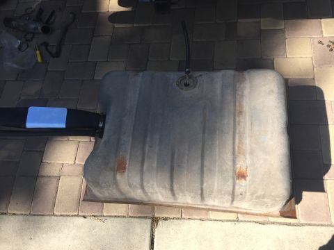1978 Ford Bronco - A large, rectangular metal fuel tank with a black hose attached to the top is resting on a paver patio. The tank appears to be from a vehic…