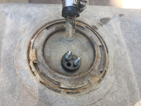 1978 Ford Bronco - A close-up view of a rusty fuel pump sender unit assembly mounted on a metal fuel tank. The assembly includes a black plastic connector wit…