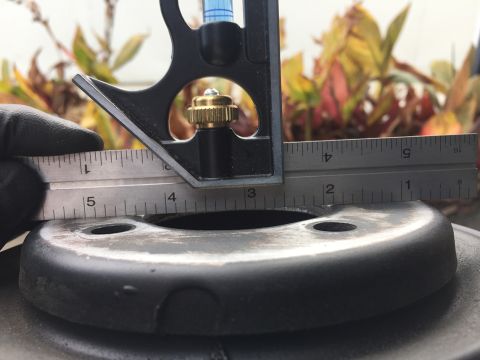 1978 Ford Bronco - A close-up shot shows a metal measurement tool, likely a combination square, being used to measure the diameter of a black, circular automo…
