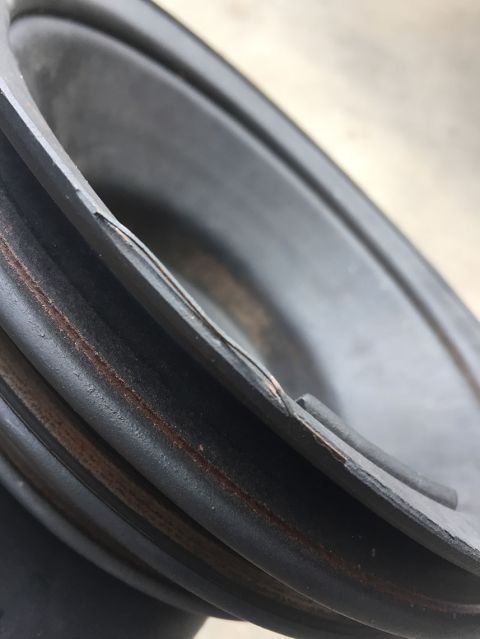 1978 Ford Bronco - A close-up, angled shot shows the damaged rubber surround of a speaker cone, with a visible tear and rust marks on the cone's edge.