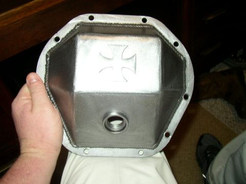 1995 Ford Bronco - Metal differential cover with an embossed Iron Cross emblem is held by a hand.