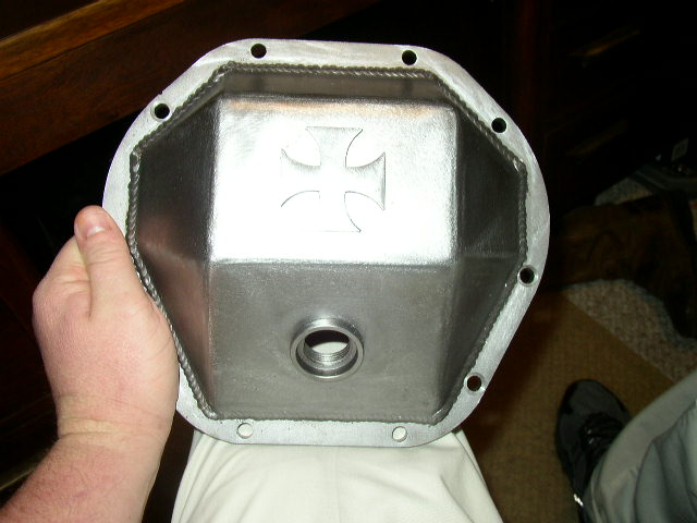 Hand holding a metal differential cover with an embossed Iron Cross