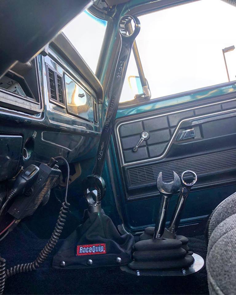 Custom gear shifter in a vintage vehicle interior with large wrench handle and two smaller wrenches.
