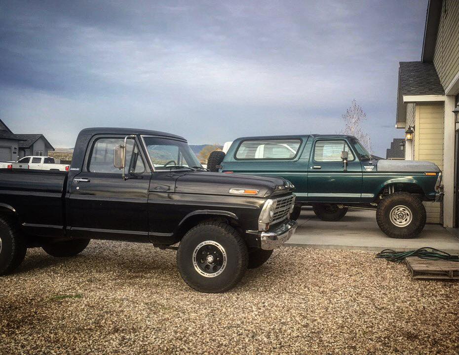 Lifted dark green 1979 Ford Bronco parked next to a black pickup truck.