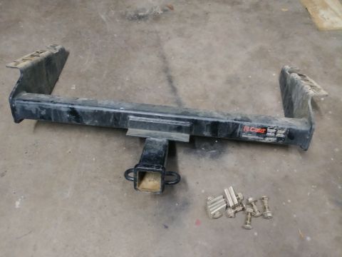 1996 Ford Bronco - A black CURT brand trailer hitch receiver is shown on a concrete floor, along with a set of bolts and washers. The hitch has a 2-inch recei…