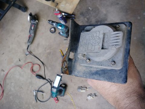 1996 Ford Bronco - A close-up view of a rusty trailer hitch connector plate with a Ford logo, held by a person's hand. Tools and wires are scattered on the co…
