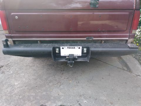 1996 Ford Bronco - The rear of a dark red Ford Bronco is shown with a black aftermarket bumper and a trailer hitch receiver. A Texas license plate is mounted…