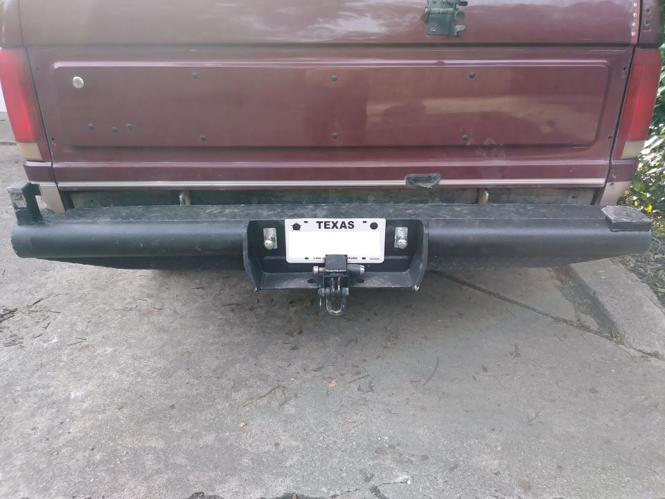 Rear view of a dark red Ford Bronco with a black aftermarket bumper and trailer hitch.