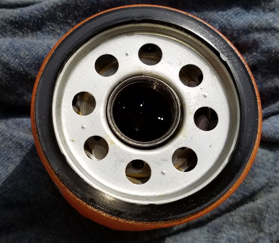 Oil filter with orange exterior and silver end cap with holes.