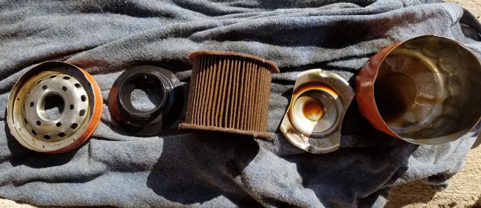 Disassembled oil filter components on a blue cloth.