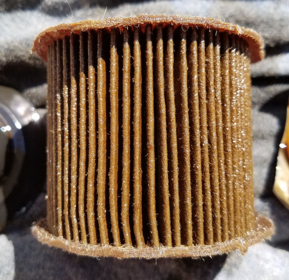 Used brown oil filter with pleated paper media.