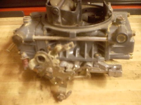 1989 Ford Bronco - A close-up view of a carburetor, likely for an older vehicle, is shown on a wooden surface.