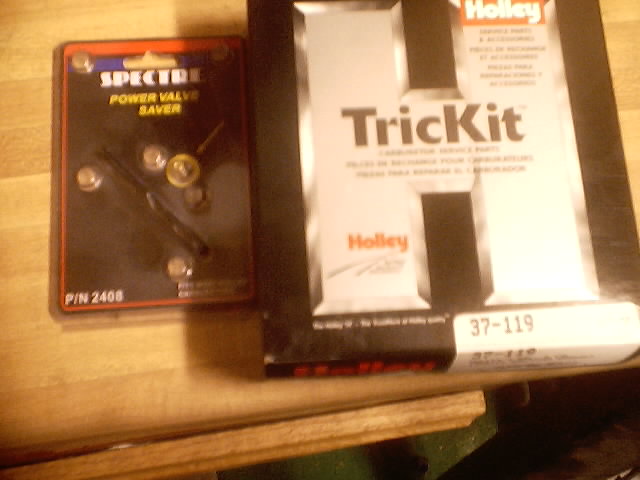 Spectre Power Valve Saver and Holley TrickKit carburetor parts on a wooden surface
