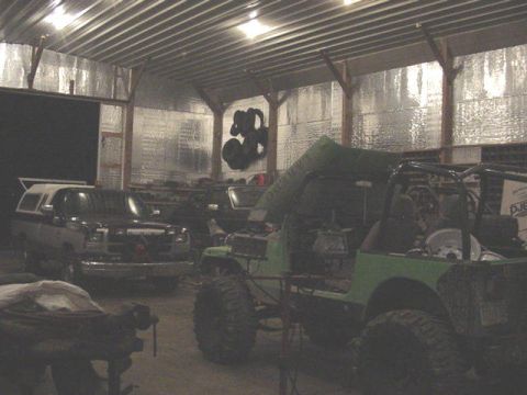 1992 Ford Bronco - Two off-road vehicles are parked inside a garage, one is green and appears to be undergoing modifications.