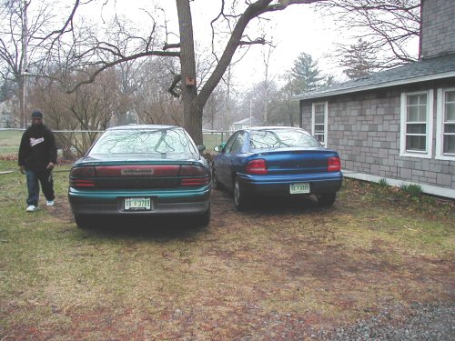 Green 1995 Dodge Intrepid and blue sedan parked in a yard with a person walking by