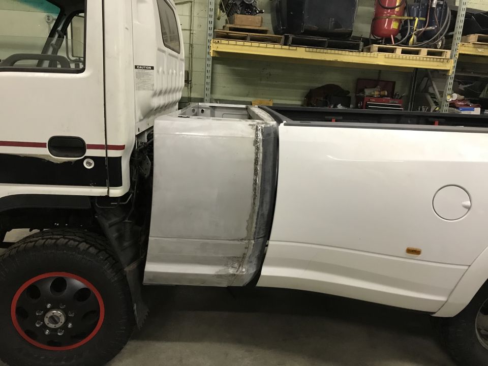 White pickup truck with custom cab extension and bed modification, side view.