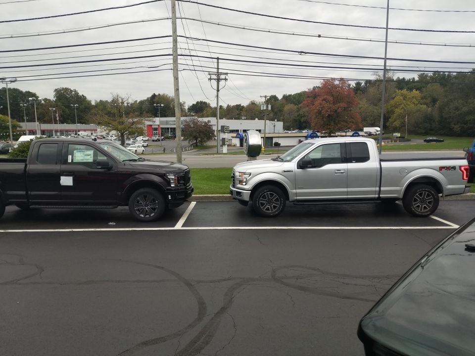 Two pickup trucks parked in a lot, one dark and one silver.