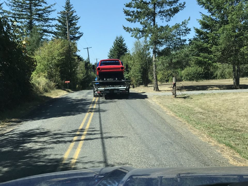 Red classic car on a flatbed tow truck from behind.