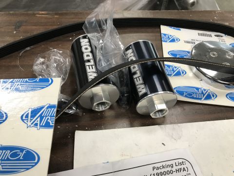 1964 Ford Fairlane - Two black "WELDON" branded inline fuel filters with silver fittings are shown with a black serpentine belt and packaging for "Vintage Air"…