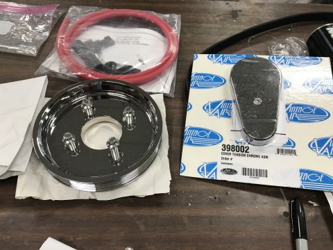 1964 Ford Fairlane - A chrome pulley with four bolts is shown next to a Vintage Air product box labeled "COVER TENSION CHROME ASM 398002". A red hose in plastic…