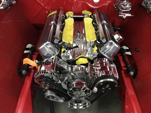 1964 Ford Fairlane - A highly polished chrome engine is installed in a red vehicle. The engine features prominent valve covers with yellow tape protecting them.