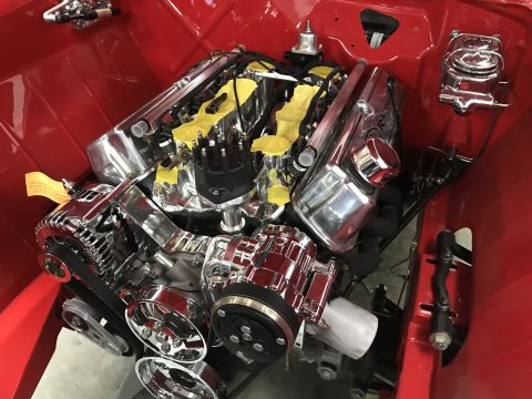 1964 Ford Fairlane - A highly polished chrome engine is installed in the red engine bay of a classic vehicle. The engine features a V8 configuration with dual v…