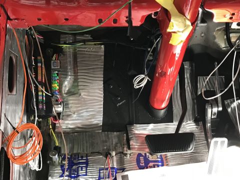 1964 Ford Fairlane - The interior of a classic car shows a red painted steering column, a fuse box with colorful fuses, and various wires and sound deadening ma…