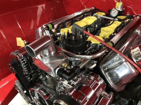 1964 Ford Fairlane - Close-up view of a highly polished V8 engine with chrome components and red spark plug wires, installed in a red vehicle.