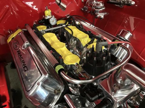 1964 Ford Fairlane - A close-up, high-angle view of a highly polished Ford Racing V8 engine bay in a red vehicle. Visible components include a distributor, spar…